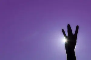 A silhouette of a hand making the UW husky "W" sign