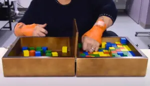 A study participant in the UW Medicine Mortiz Lab practices moving blocks with the help of noninvasive spinal electrical stimulation applied to the skin.