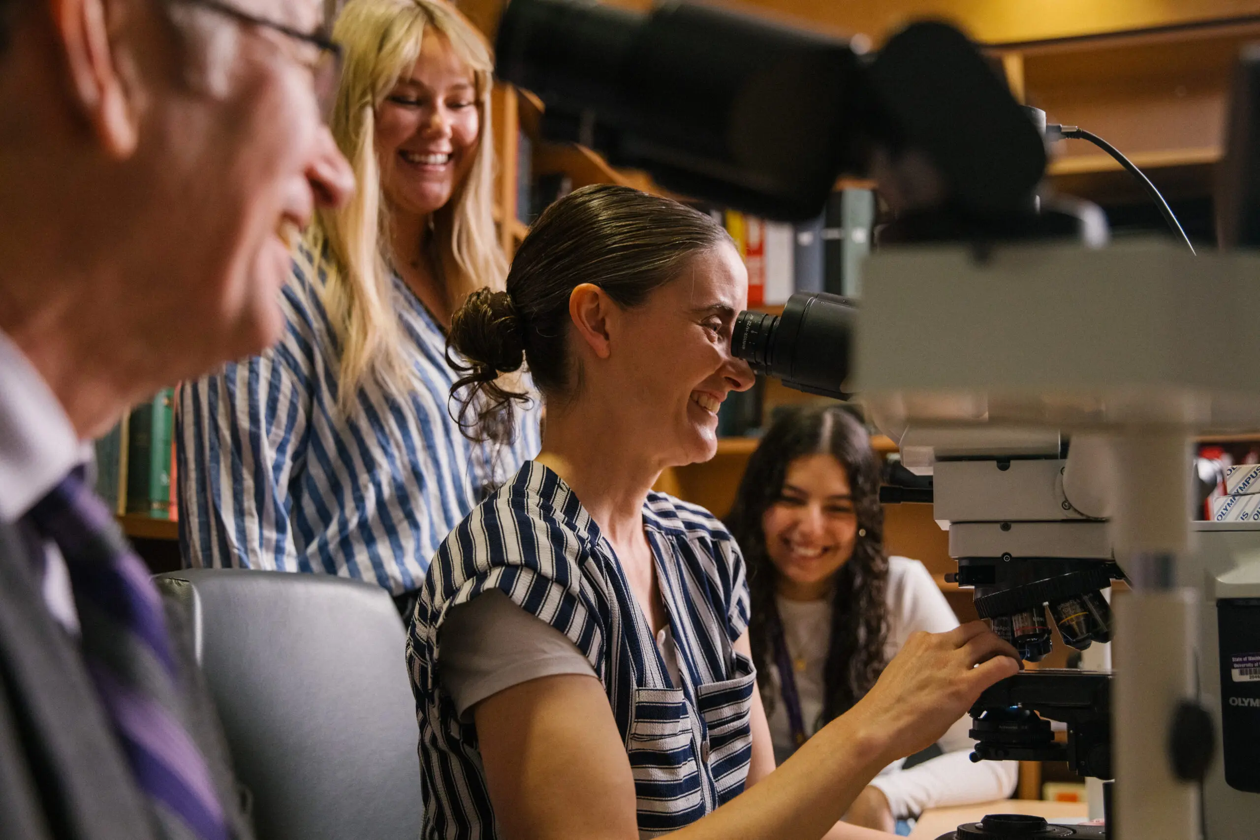 Researchers laugh while examining slides under a microscope at the Alzheimer's Disease Research Center
