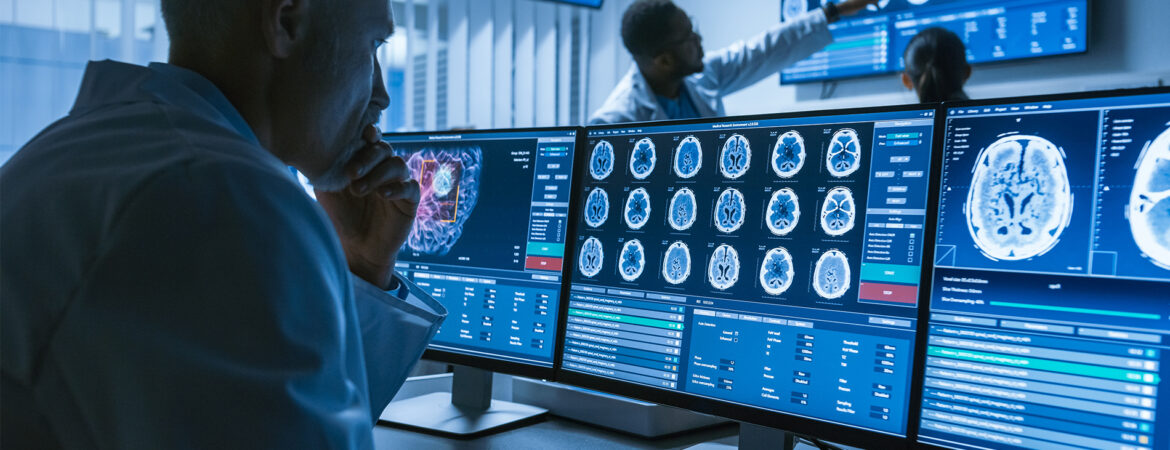 Researcher studying brain scans on computer monitors.