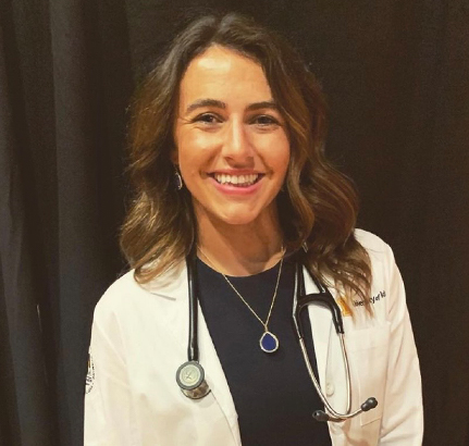 Christina Gibbs in a white coat and stethoscope