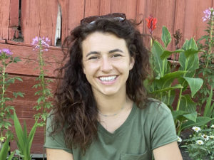 photo of Christina Gibbs sitting in front of flowers and a fence