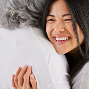 A person smiles into the distance while embracing another person wearing a white coat.