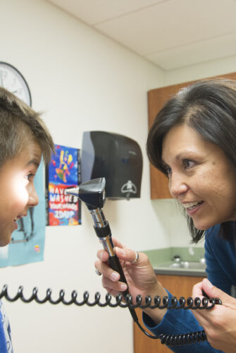 Dr. LeeAnna Muzquiz, WWAMI instructor, family medicine, performs a physical exam on a child patient at the Tribal Health Clinic in Polson, MT.