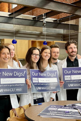UW School of Medicine Spokane students posing with signs that read "Our New Digs!" in their new facility at Gonzaga University.