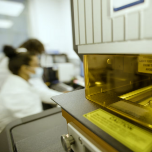 Researchers performing a test that runs a laser along the length of a hair, using its energy to turn it into a plasma for analysis.