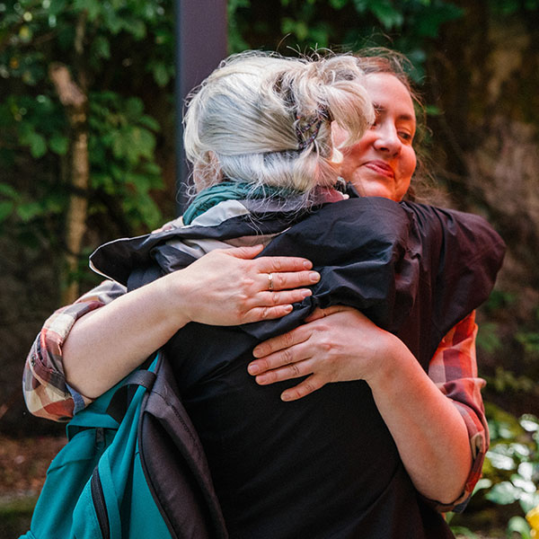 A patient and provider hug outside in the garden at the Memory Hub.
