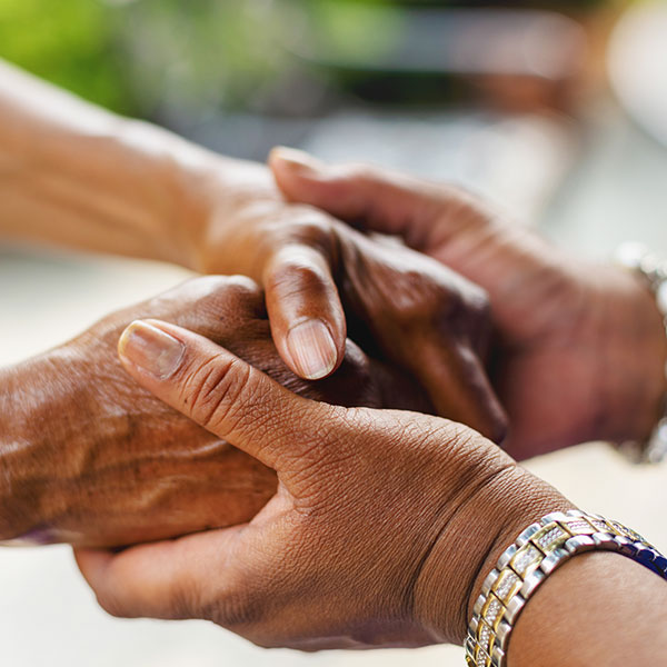 Two people clasping hands. One wears a silver watch.
